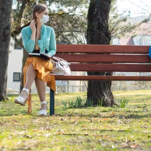 Two people keeping their distance on a park bench.