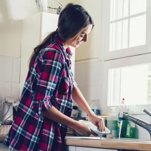 A happy woman doing the dishes.
