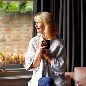 A Woman Looks at the Window with Her Cup of Tea