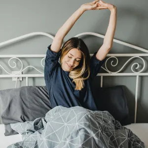 A woman stretching in bed after a good night's sleep. 