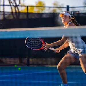 A Woman Playing Tennis Looks Across the Tennis Court as She Prepares to Return a Voley.