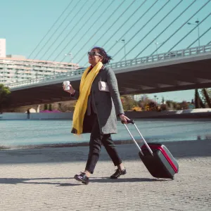 A young woman rolls her suitcase as she travels