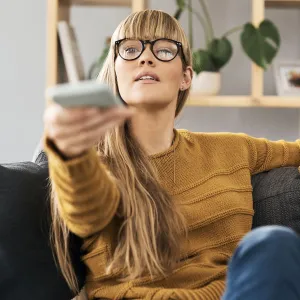 Woman at home turning on her tv.