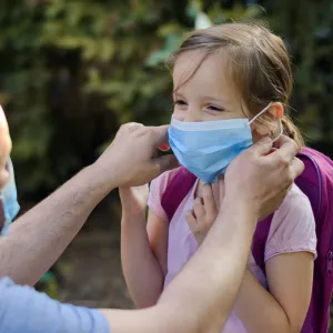 A dad helps his daughter get ready to go back to school.