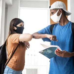 Two teenagers elbow-bumping at school