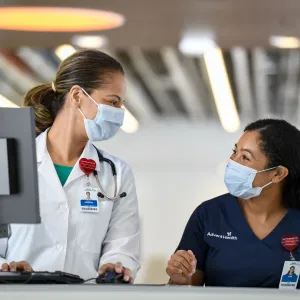 Medical professionals wearing face masks, smiling at each other.