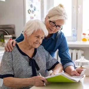 Woman with arm around mother looking at paperwork