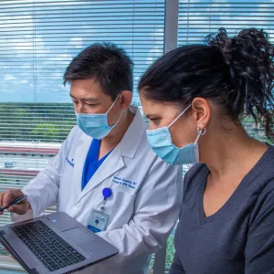 Iswanto Sucandy showing patient a something on a laptop.