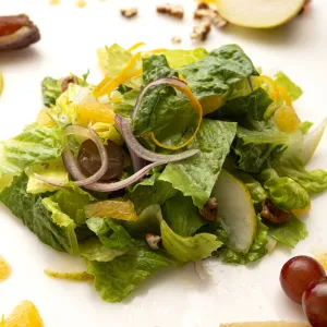 Mound of romaine salad with grape, orange, and apple garnishes