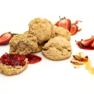 a pile of five fresh baked biscuits, topped with strawberry puree and surrounded by strawberry slices