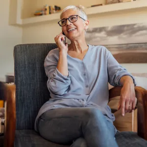 Senior woman smiling while talking on the phone while sitting at home.