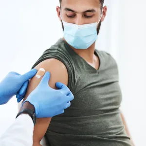 Man getting bandaged after a vaccine while wearing a mask.