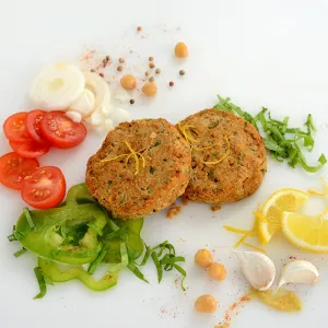 two falafel patties in the center of veggies and seasonings