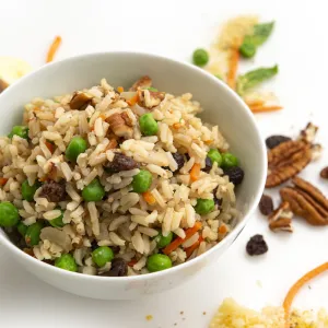 Bowl of pilaf on white counter with pecan garnish