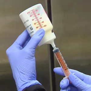 A Nurse Fills a Syringe With Breast Milk