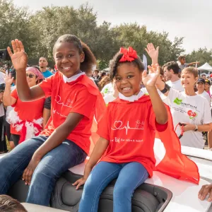 Aidyn, 8, and Aniyah, 4, ride in a parade at the American Heart Association's 2022 Greater Orlando Heart Walk held at UCF.