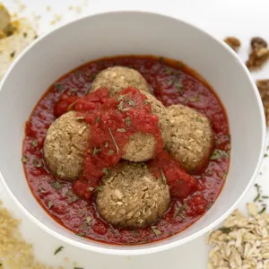 Bowl of nut balls in red sauce with breadcrumb decoration