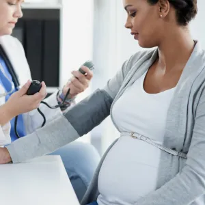 One pregnant woman getting her blood checked by a female doctor in scrubs.