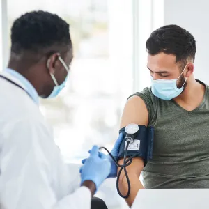 doctor with mask taking blood pressure of patient with mask