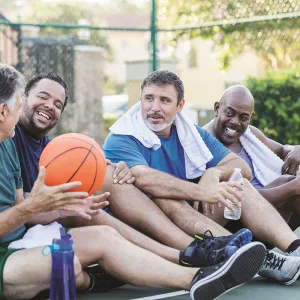 A group of men sitting down with a basket ball.