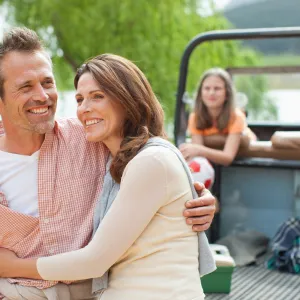 Man hugs wife with kids in the background