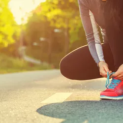 A runner ties her shoe.