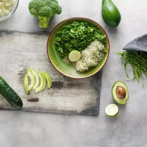 Salad bowl, produce, cutting board, towel and knife sitting on a counter.