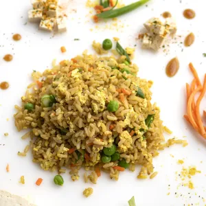 Mound of fried rice on white surface next to crackers and garnishes