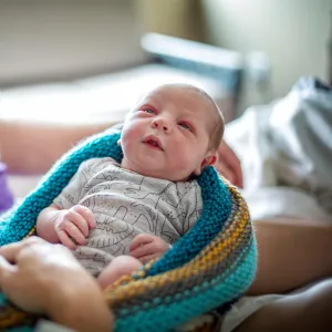 Newborn baby being held by parents in the hospital.