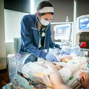 Nurse examining a newborn in the NICU.