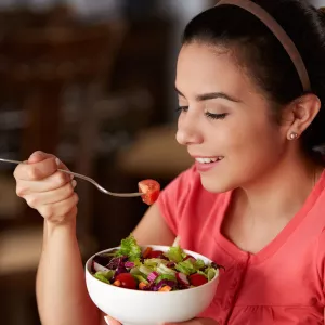 A woman eating a bowl of health food.