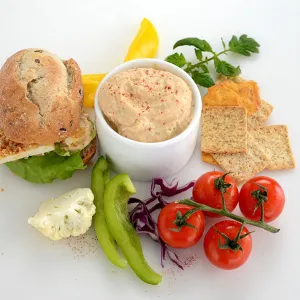 a bowl of creamy dip, surrounded by bread, crackers and fresh vegetables