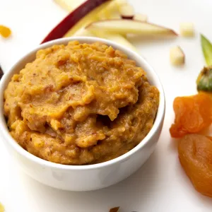 White bowl of apricot jam with dried fruit garnishes