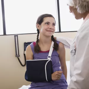 Physician talking to girl with dislocated shoulder