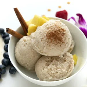 A bowl of vanilla-coconut ice cream surrounded by fresh fruit and flowers.