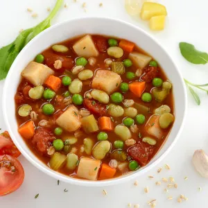 Bowl filled with soup containing barley, rice, potatoes, lima beans and carrots