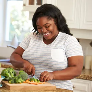 A woman chopping vegetables in the kitchen.