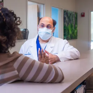 Yasser Saloum and patient wearing masks and talking.