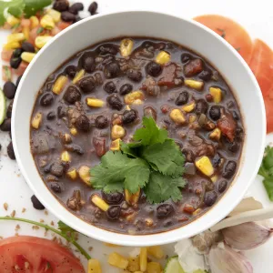 Bowl of tex-mex soup with tomato and green garnishes