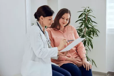 Female Doctor talking to Female Patient Showing Her Paper