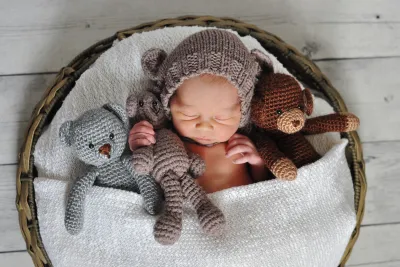 baby sleeping in basket with stuffed animals