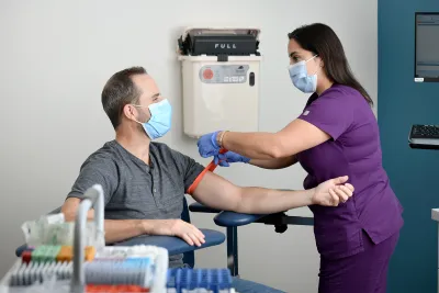 Lab technician preparing man for a blood draw.