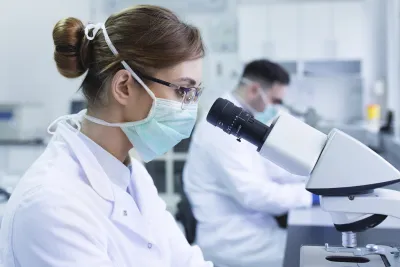 A woman looking through a microscope in a lab.