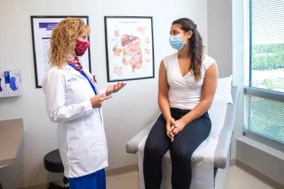 Doctor Sharona Ross talking with patient while wearing masks.