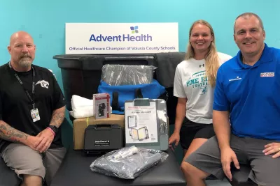 Two man and a woman sitting around heat illness Supplies. 