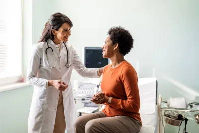 A woman talking with her doctor in an exam in room.