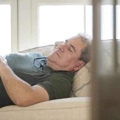 An adult Caucasian man takes an afternoon nap on the couch.