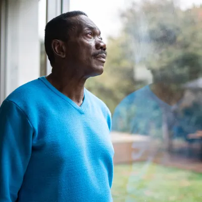 An African American Man Looks Out a Window into the Forest.