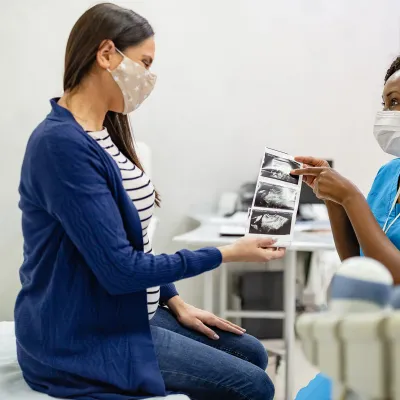 A Woman Looks Over The Sonogram of Her Baby with Her Physician.