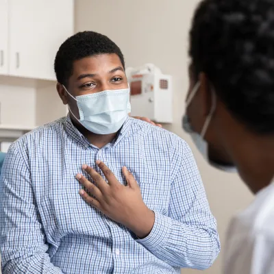 A Man Speaks to His Doctor in a Patient Room While Being Comforted with a Family Member.